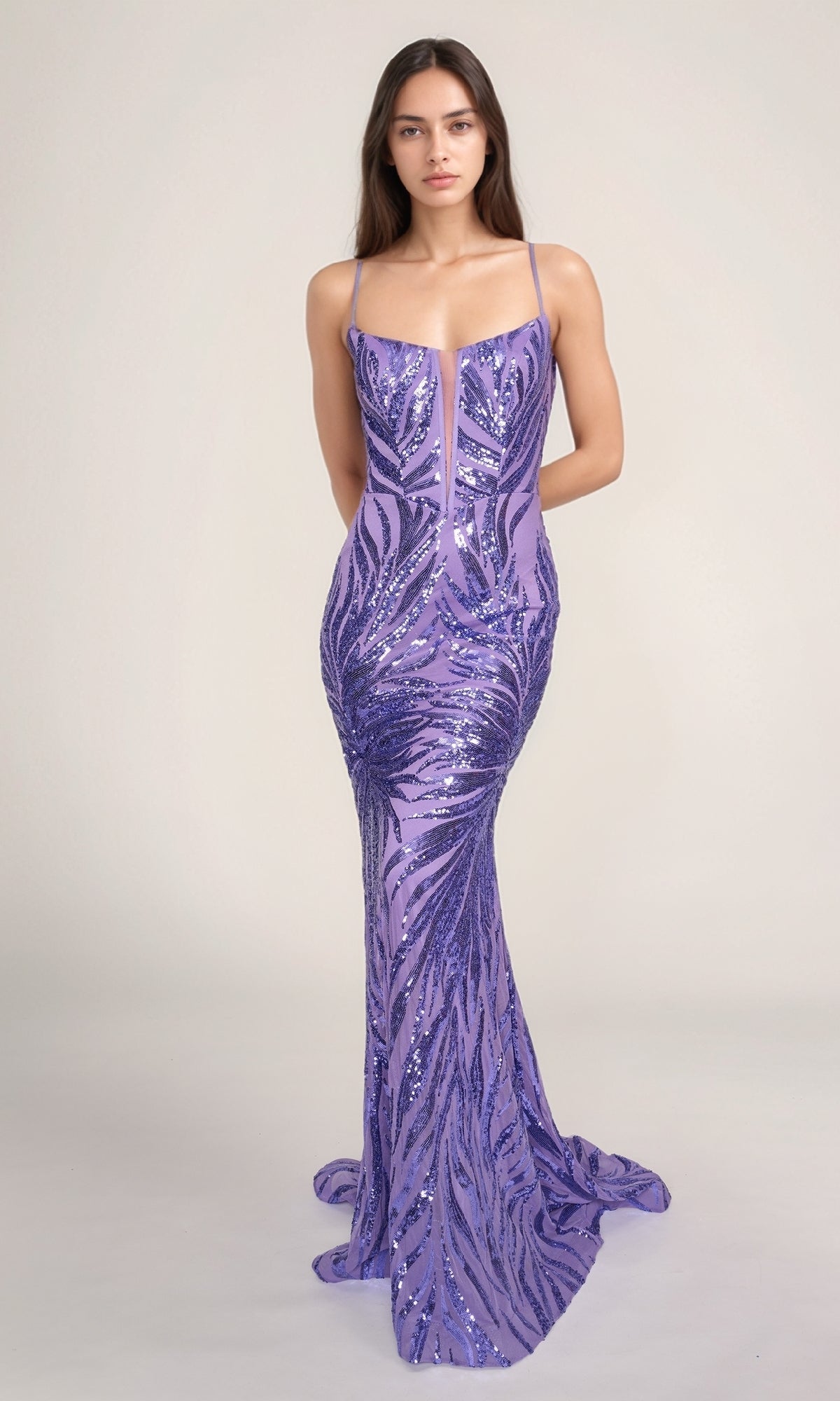 A woman wearing the Nina Canacci 4433, a fitted floor-length lavender sequin prom dress with a lace-up open back, stands against a plain light background.